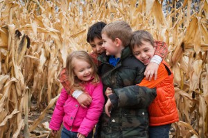 Kids and their mother playing in the corn field in the fall.