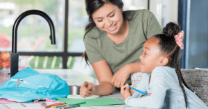 after school sitter helping child with homework at kitchen counter