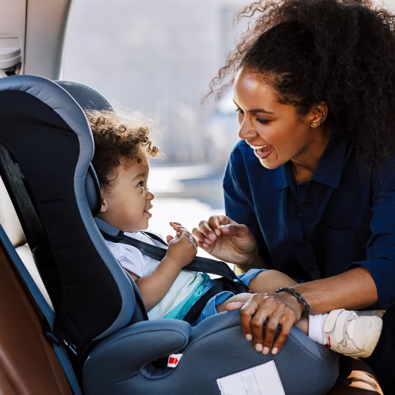 Natalie's sitter buckling child into car seat