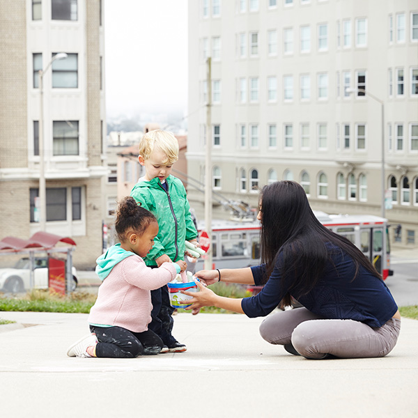 Babysitter playing with children at a park