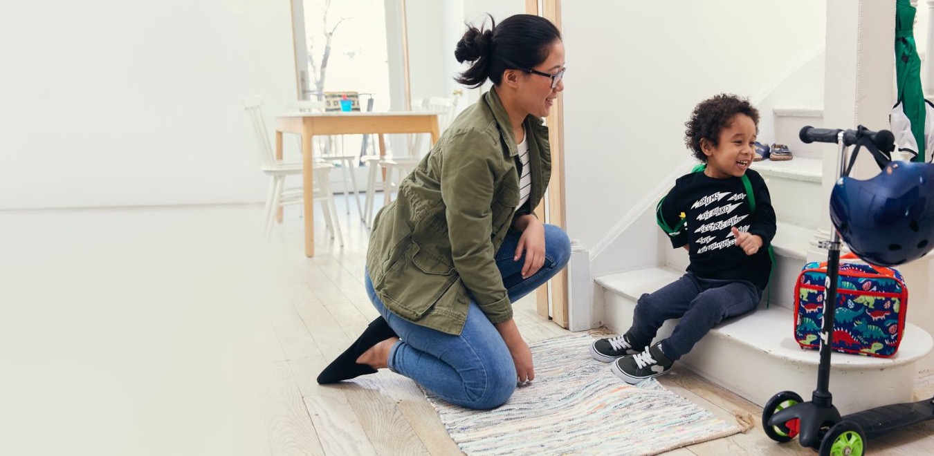 Babysitter helping child ride a scooter outdoors