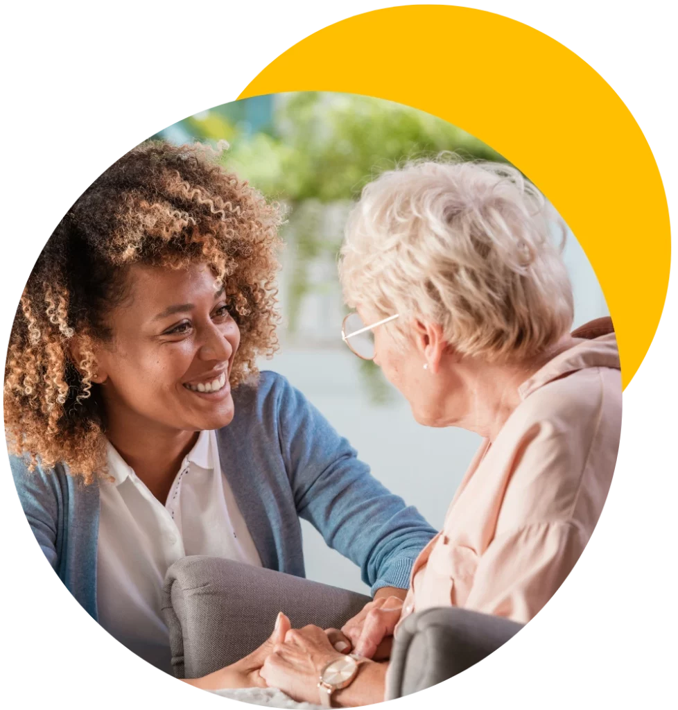 senior caregiver smiling and comforting elderly woman