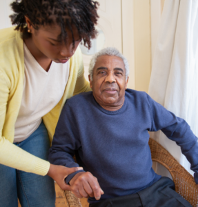 elderly caregiver helping man sitting in chair