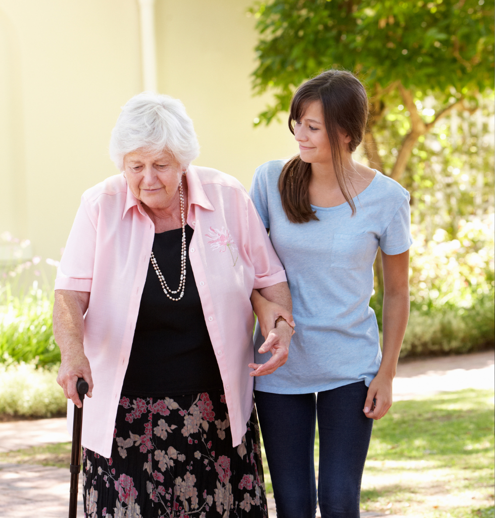 elderly care provider walking with woman holding cane